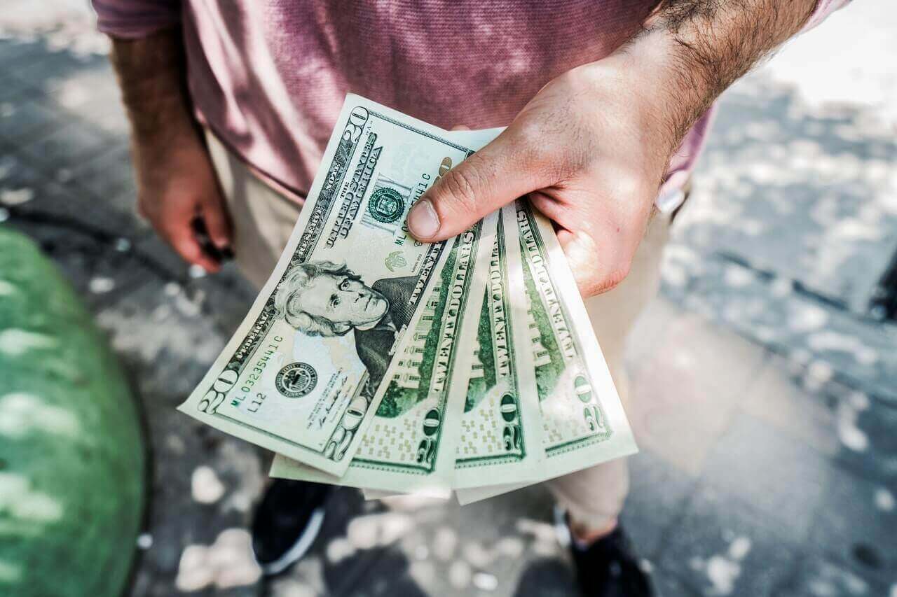 Person holding out a fan of four twenty dollar bills