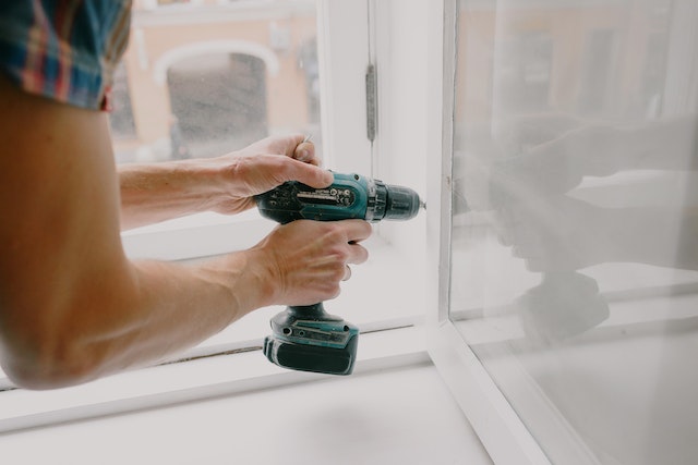 Close up of someone using a drill on a window