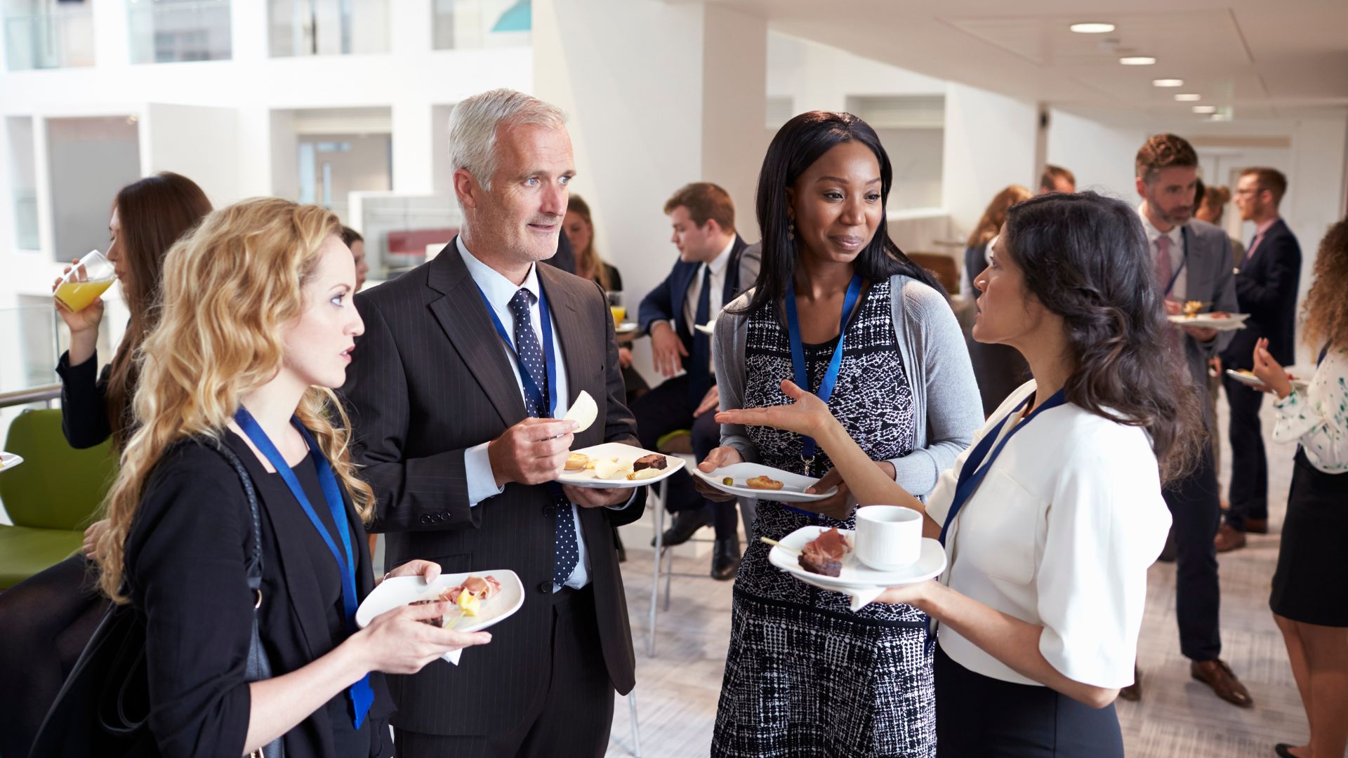 four colleagues in suits speaking to one another