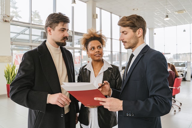 Three people standing together looking at a document