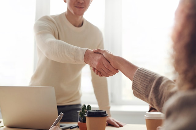 two people shaking hands across table