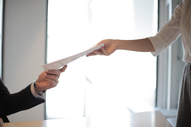 Close up of one person handing a mortgage document to another person