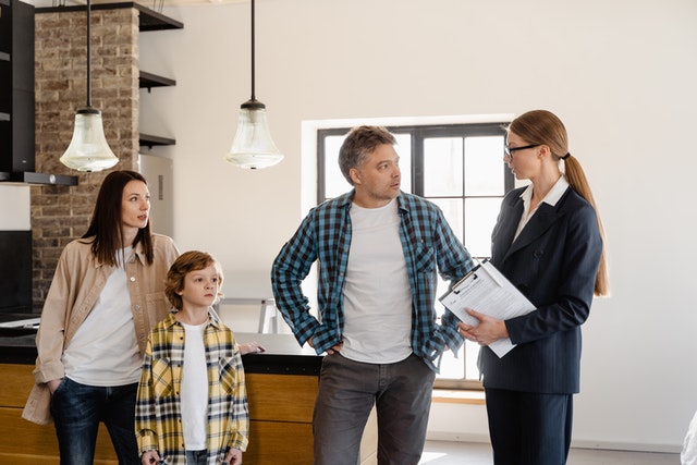 A real estate agent showing an investment property to a family of two adults and a child