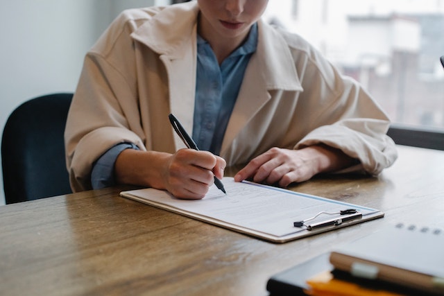 Person writing on a clipboard