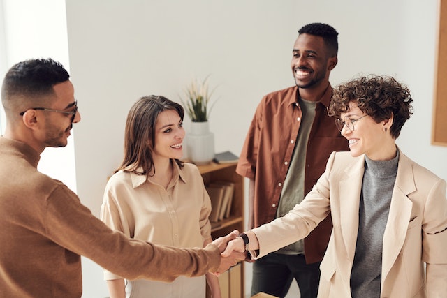 two people shaking hands with two other people smiling