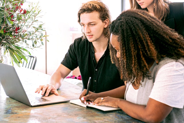 A real estate attorney working on a computer explaining something to two other people