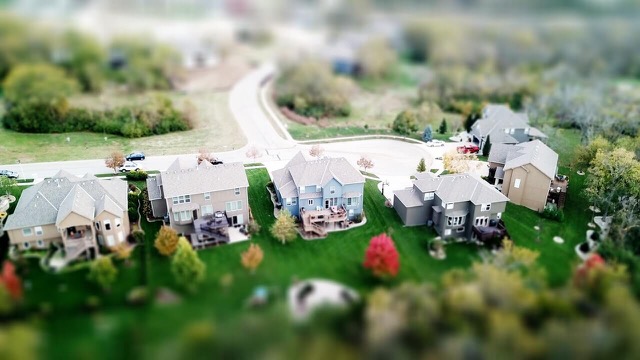 Birds-eye view of a street in the Fort Worth area with five large houses, green lawns, and trees.